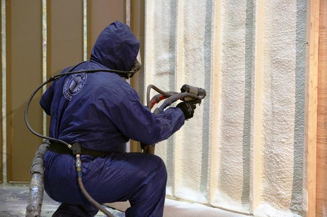 A man spraying insulation on a wall